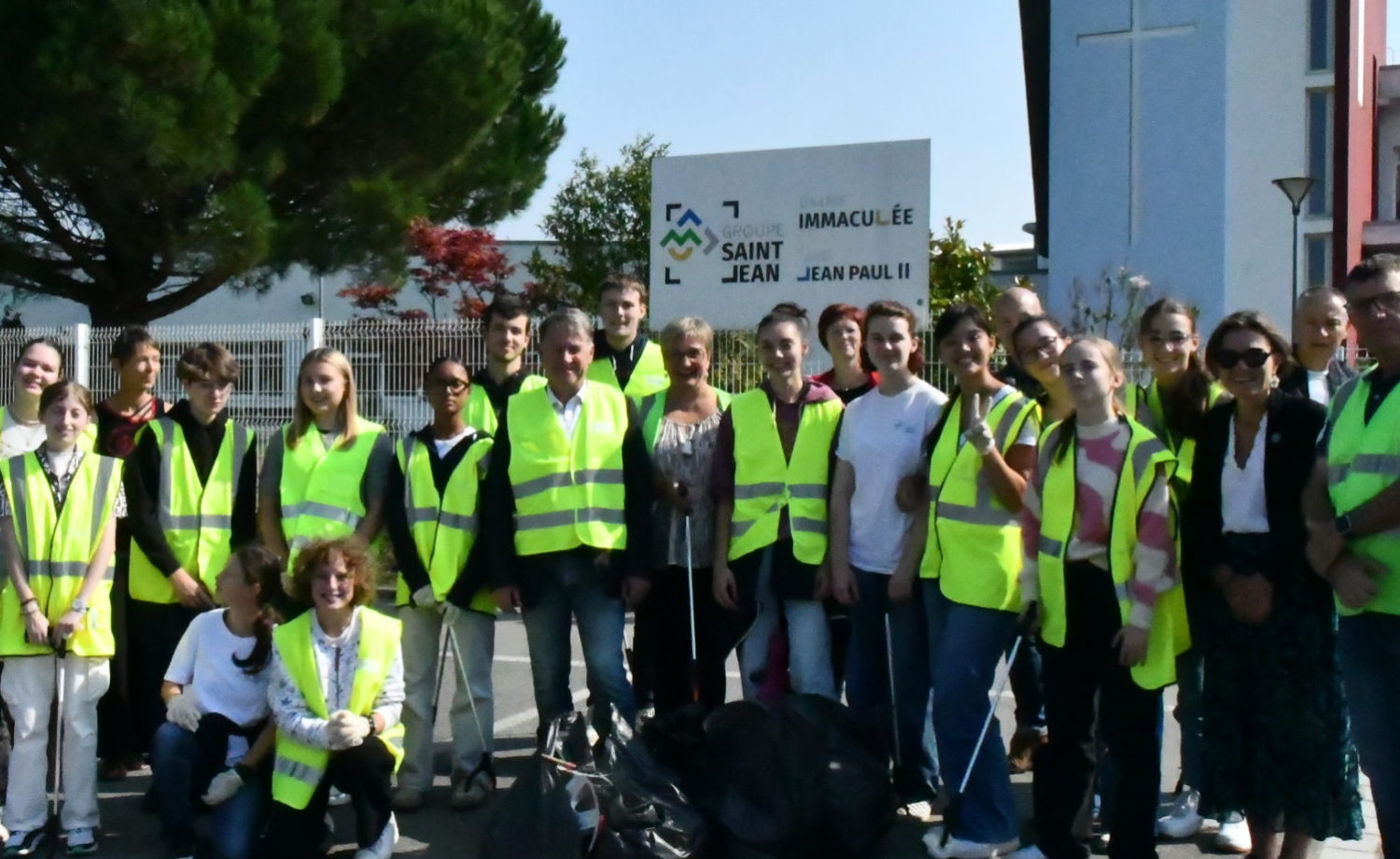 Élèves et adultes du Lycée Jean-Paul II équipés de gants, pinces et sacs poubelles, ramassant des déchets autour du lycée lors du World Cleanup Day 2024.