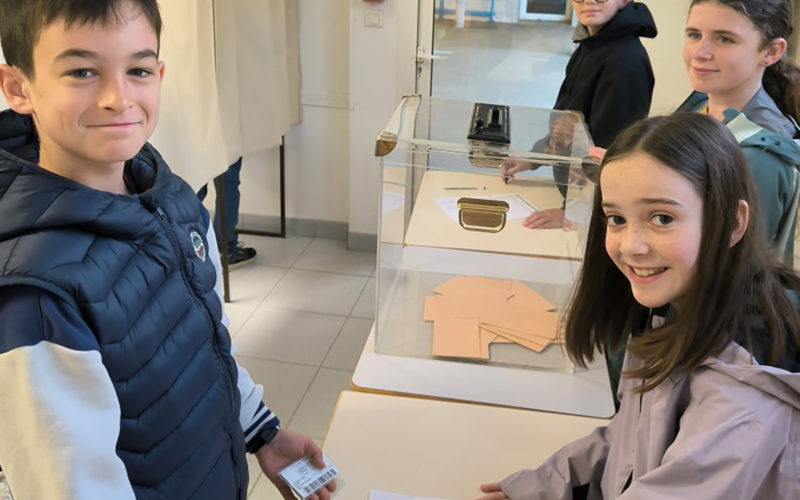 Des élèves de 6ème en train de participer activement aux élections de leurs délégués de classe, devant des urnes et des isoloirs dans un cadre scolaire.