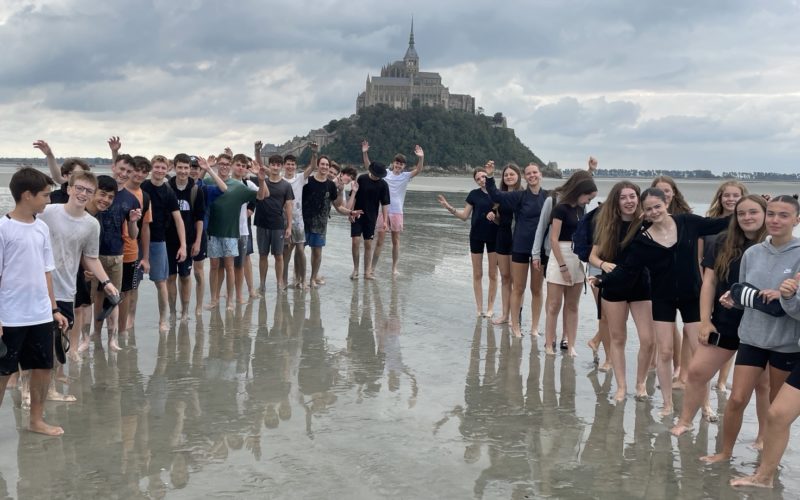 Élèves de Seconde du Lycée Jean-Paul II traversant la baie du Mont-Saint-Michel sous le soleil, entre jeux, découvertes historiques et franchissement des sables mouvants.