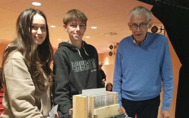 Marc Raynaud présente la machine de Turing aux élèves de terminale, entouré de plusieurs modèles de cette invention iconique, illustrant les concepts d'algorithmes, de mémoire et de calcul.